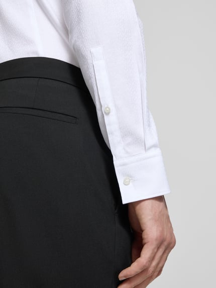 Männermodel trägt Slim Fit Freizeithemd aus reiner Baumwolle Modell 'KENNO' von HUGO in Weiß mit feinem Strukturmuster, Nahaufnahme Unterarm.