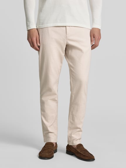 Męski model nosi Regular Fit Chino aus Baumwoll-Mix od Tom Tailor, jasnobeżowy melanż, bawełniany materiał, boczne kieszenie, widok z przodu, zbliżenie na dolną część ciała.