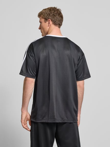 Männermodel trägt Funktionsshirt mit Logo und Rundhalsausschnitt von adidas Originals, schwarz mit weißen Kontraststreifen, Regular Fit, Rückenlänge 75 cm, Ganzkörperansicht Rückansicht.