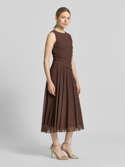 Frauenmodel trägt Midikleid aus Mesh in asymmetrischem Look von Christian Berg Woman Selection in Braun, Gerader-Schnitt, Rundhalsausschnitt, Ganzkörperansicht von vorne. Rückenlänge bei Größe 36: 50 cm, Brustweite bei Größe 36: 39 cm.