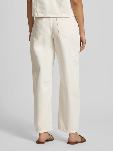 Modelka nosi Wide Fit Jeans in verkürzter Passform Modell 'Dexter' von MSCH Copenhagen z bawełny, 5 kieszeni, zapięcie na guzik i zamek błyskawiczny, szerokość w rozmiarze S: 38 cm, długość wewnętrzna nogawki w rozmiarze S: 74 cm, kremowa kolorystyka, widoczne fakturalne przeszycia, widok całej sylwetki z tyłu.