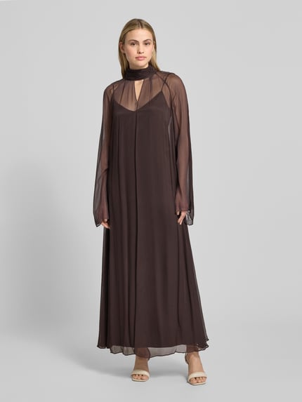 Vrouwenmodel draagt Maxikleid aus Viskose mit Stehkragen Modell 'ESTHER' van Staud in semitransparant bruin, losse pasvorm, geheelvooraanzicht.