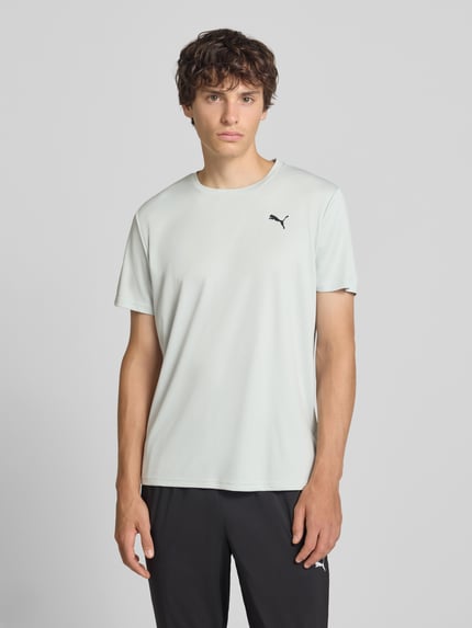 Männermodel trägt Regular Fit Sport-T-Shirt mit Logo-Print Modell 'TAD Essential' van PUMA Performance in lichtgrijs, gladde stof, Ganzkörperansicht von vorne
