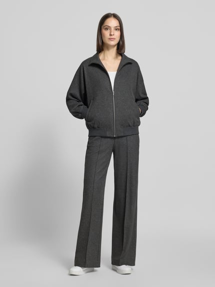 Frauenmodel trägt Jacke aus Viskose-Mix Modell 'EYAM' von DRYKORN in Grau, mit Stehkragen und Reißverschluss, Regular Fit, Ganzkörperansicht von vorne. Viskose-Mix mit Stretch-Anteil, Eingrifftaschen, Rückenlänge 59 cm, Brustweite 70 cm, Ärmellänge 48 cm.