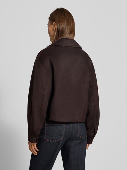 Frauenmodel trägt Jacke mit Eingrifftaschen Modell 'CANDYX' von MANGO in Dunkelbraun, Material-Mix, gerade Passform, Ganzkörperansicht Rückansicht.