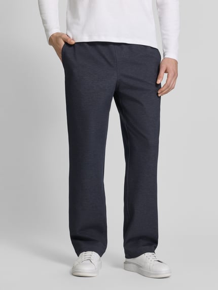 Männermodel trägt Straight Fit Stoffhose aus elastischem Viskose-Mix von GUESS in Dunkelblau mit elastischem Bund, Nahaufnahme Oberkörper. Modell 'DRIFTER', elastischer Tunnelzug, Bundweite Größe M: 46 cm, Innenbeinlänge Größe M: 82 cm.