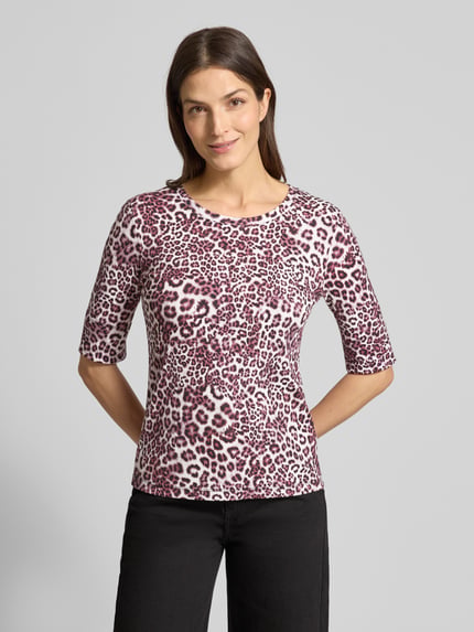 Kobiece modelka nosi Damski t-shirt T-Shirt mit Rundhalsausschnitt von Marc Cain, mieszanka bawełny i elastanu, krój slim fit, okrągły dekolt, rękaw o dł. 1/2, długość tyłu w rozmiarze 36: 55 cm, wzór w panterkę w odcieniach różu i bieli, tekstura gładka, pełny widok z przodu.