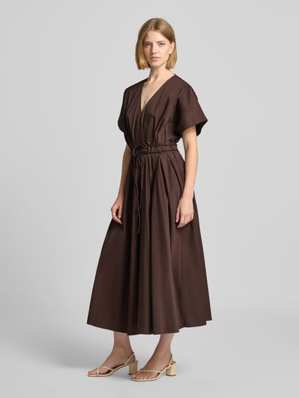 Frauenmodel trägt Cocktailkleid mit V-Ausschnitt und Schnürung von Christian Berg Cocktail, braun, A-Linie, Midikleid, Ganzkörperansicht von vorne.