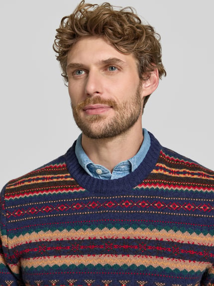 Männermodel trägt Slim Fit Strickpullover aus Baumwoll-Mix mit Rundhalsausschnitt von MCNEAL, farbenfrohes Muster, Nahaufnahme Oberkörper.