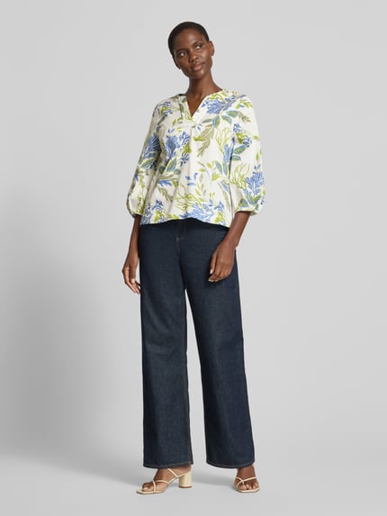 Modelka nosi Bluse mit 3/4-Arm und Tunikakragen od ETERNA z czystej bawełny, krój loose fit, tunikowy kołnierz, rękawy 3/4, kolorowy kwiatowy wzór, długość tyłu w rozmiarze 36: 60 cm, długość rękawa w rozmiarze 36: 47 cm, pełny widok z przodu.