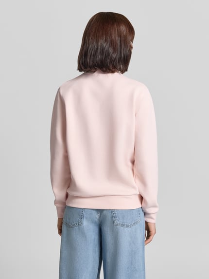 Frauenmodel trägt Relaxed Fit Sweatshirt aus Baumwoll-Mix von Lacoste in zartem Rosa, glatte Struktur, dezente Nähte, Ganzkörperansicht Rückansicht. Damen Sweatshirt von Lacoste.