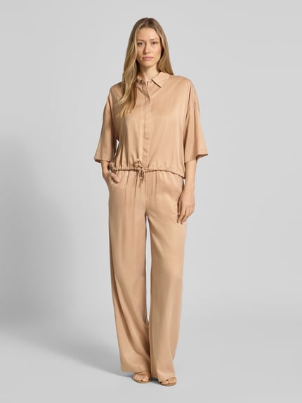 Frauenmodel trägt Wide Fit Stoffhose mit elastischem Bund Modell 'Consider' von Drykorn, Cupro-Mix in Beige, strukturierte Oberfläche, Ganzkörperansicht von vorne.
