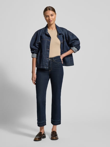 Frauenmodel trägt Feminine Fit Jeans in verkürzter Passform von Marc Cain, dunkle Baumwoll-Elasthan-Mix, Ganzkörperansicht von vorne.