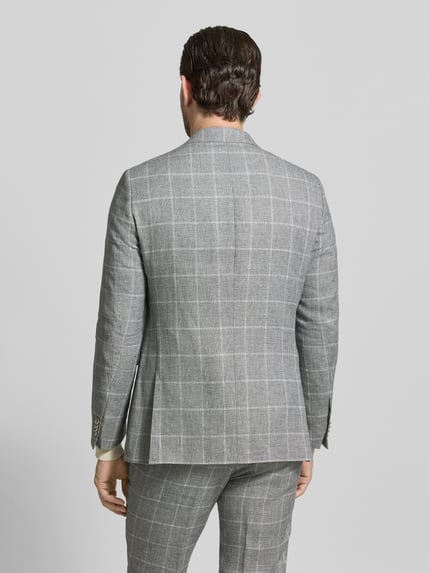 Männermodel trägt Slim Fit Anzug mit 2-Knopf-Sakko Modell 'Paul/Paco' von CG - Club of Gents in Hellgrau mit Karomuster, Ganzkörperansicht Rückansicht.