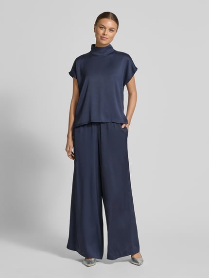Frauenmodel trägt Hose mit weitem Bein Modell 'TWEEZER' von Drykorn in Dunkelblau, Material-Mix, elastischer Bund, Eingrifftaschen, Ganzkörperansicht von vorne.