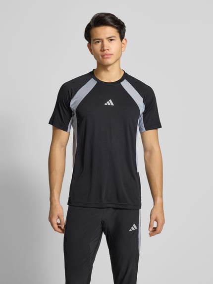 Męski model nosi T-Shirt z label-print od adidas Training w kolorze czarnym z szarymi akcentami, regular fit, widok z przodu, górna część ciała.