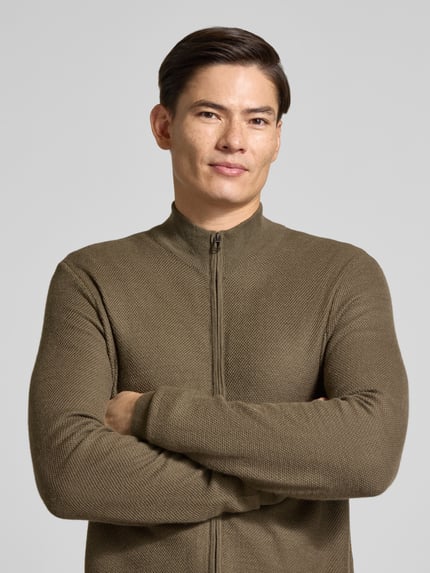 Männermodel trägt Strickjacke aus Wolle mit Stehkragen von JOOP!, unifarben, Strickoptik, Reißverschluss, Nahaufnahme Oberkörper.