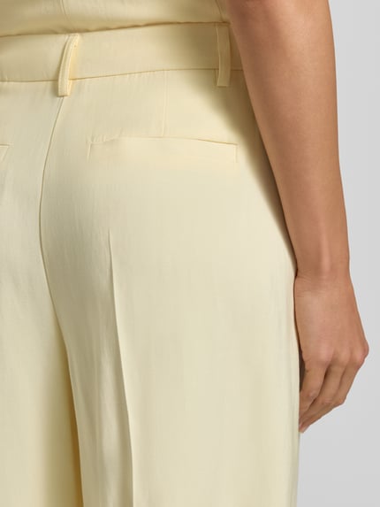 Frauenmodel trägt Bermudas aus Viskose-Mix Modell 'ESSIE' von B.Young in hellem Gelb mit Bügelfalten, Detailaufnahme Rückansicht. Bundweite bei Größe 36: 37 cm, Innenbeinlänge bei Größe 36: 28 cm, Regular-Fit, weiche Oberfläche.