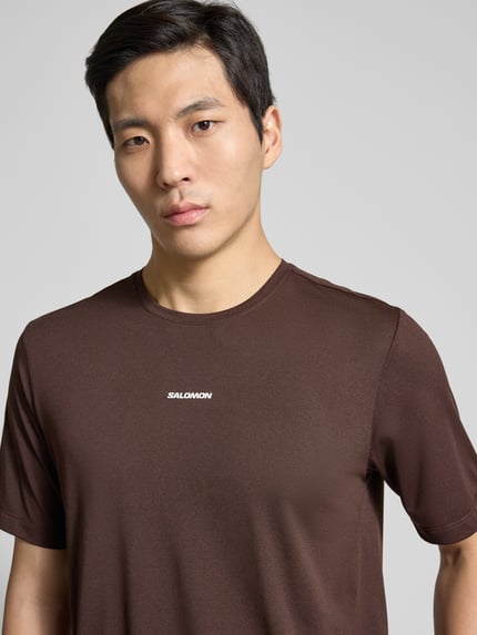 Mannelijk model draagt Funktionsshirt met logo en ronde hals model 'Kout' van Salomon in regular fit, ruglengte maat M 69 cm, nahaufnahme bovenlichaam.