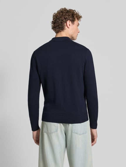 Männermodel trägt Slim Fit Poloshirt aus reiner Baumwolle von ARMEDANGELS in Dunkelblau, glatte Struktur, Ganzkörperansicht Rückansicht.