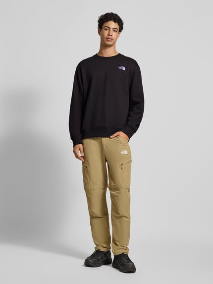 Männermodel draagt zwart Sweatshirt met labelprint van The North Face van puur katoen, relaxed fit, ribboorden, ronde hals, geheel vooraanzicht.