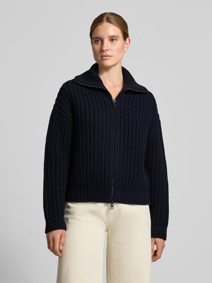 Frauenmodel trägt Strickjacke aus Wolle mit Umlegekragen von Closed in Dunkelblau, grob gestrickte Textur, Straight Fit, Zweiwege-Reißverschluss, Ganzkörperansicht von vorne.