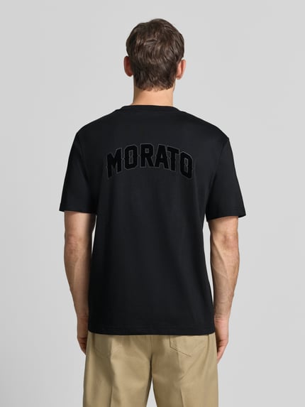 Männermodel trägt Relaxed Fit T-Shirt aus puur katoen van Antony Morato in zwart met labelpatch, ruglengte maat M 70 cm, Ganzkörperansicht Rückansicht.