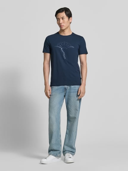 Männermodel trägt T-Shirt mit Rundhalsausschnitt Modell 'Alerio' von JOOP! Collection in Dunkelblau, Reine Baumwolle, Regular-Fit, Logo, Ganzkörperansicht von vorne.
