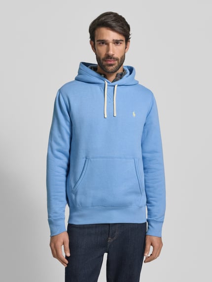Männermodel trägt Hoodie mit Label-Stitching von Polo Ralph Lauren in Hellblau mit Känguru-Tasche, lockerer Schnitt, Ganzkörperansicht von vorne.