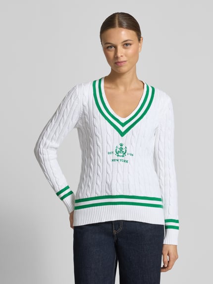 Frauenmodel trägt Slim Fit Pullover in Strick-Optik Modell 'Meren' von Lauren Ralph Lauren aus reiner Baumwolle mit V-Ausschnitt, Weiß mit grünen Akzenten, Logo-Ausschnitt, elastische Abschlüsse, Ganzkörperansicht von vorne.