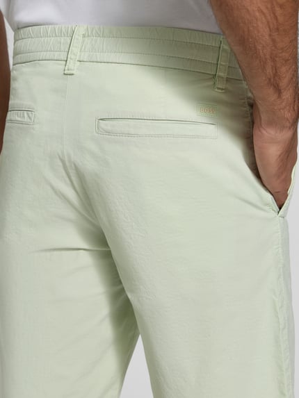 Männermodel trägt Tapered Chinoshorts aus Baumwoll-Mix Modell 'CHINO_TAPERED_DS_3S' von BOSS Orange, unifarben, Nahaufnahme Rückansicht.