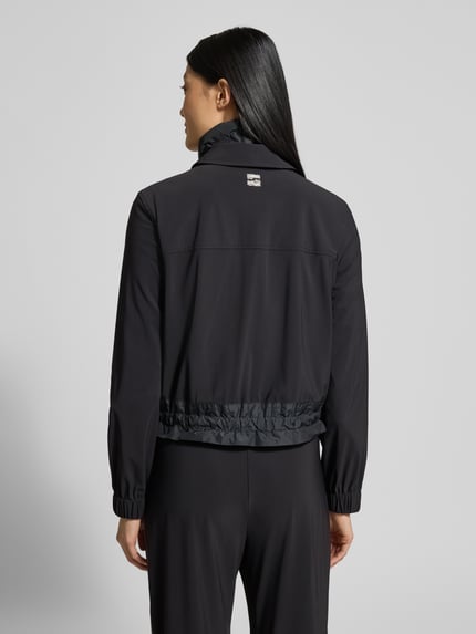 Männermodel trägt Blazer mit Stehkragen von Marc Cain w kolorze czarnym, materiał z domieszką stretchu, długość do bioder, widok z tyłu, Ganzkörperansicht Rückansicht.