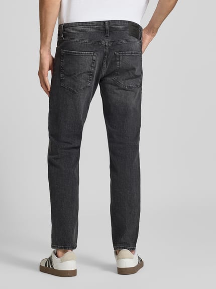 Männermodel trägt Regular Fit Straight Fit Jeans mit Label-Patch von JACK & JONES in dunkler Used-Optik, Ganzkörperansicht Rückansicht.
