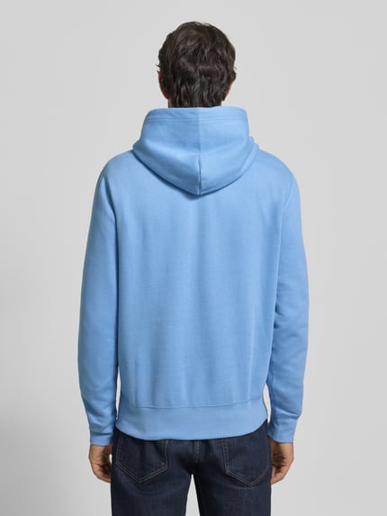 Männermodel trägt Hoodie mit Label-Stitching von Polo Ralph Lauren in Hellblau aus Baumwoll-Mix, lockerer Schnitt, Ganzkörperansicht Rückansicht.