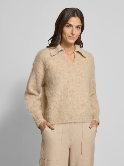 Frauenmodel trägt Strickpullover mit gerippten Abschlüssen Modell 'Pelsie' von OPUS, beżowy, luźny krój, miękka faktura, całkowity przód, materiał-mix z wełną, dekolt V, kołnierz resort, efekt subtelnej tekstury. Ganzkörperansicht von vorne.