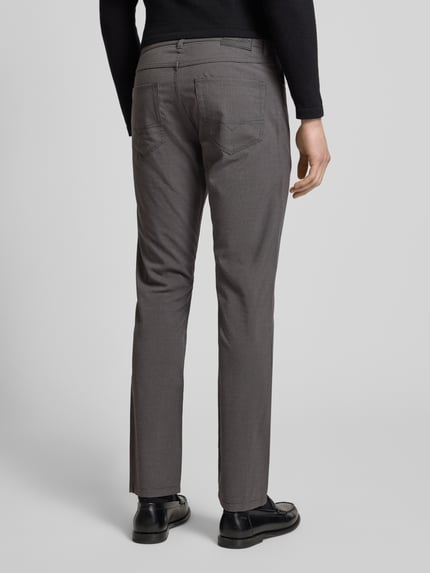 Männermodel trägt Chino mit 5-Pocket-Design von Christian Berg Men aus Material-Mix mit Viskose-Anteil, graue Farbe, Gerader-Schnitt, Ganzkörperansicht Rückansicht.