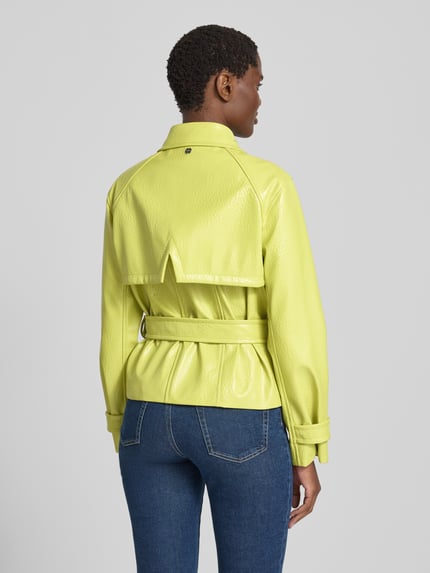 Frauenmodel trägt Jacke mit Gürtel und Ärmelriegeln von Marc Cain in Gelb, strukturierte Oberfläche, Rückenlänge 58 cm, Ganzkörperansicht Rückansicht