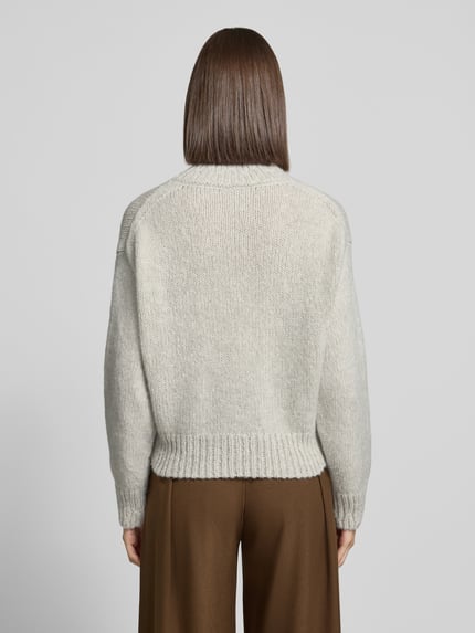 Modelka prezentuje sweter wełniany z alpaki z prążkowanymi ściągaczami od MARC CAIN, krój regular fit, jednokolorowy, imitacja dzianiny, krój krótki, długie rękawy z opuszczonymi ramionami, okrągły dekolt, wykończenia i ściągacze prążkowane, widok sylwetki od tyłu