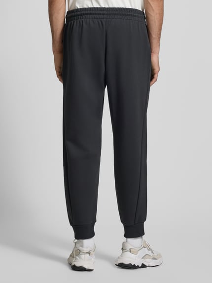 Männermodel trägt Sweatpants mit Logo und elastischem Bund von adidas Sportswear, Materiaalmix met katoen, regular fit, elastische band, tunnelkoord, binnenbeenlengte bij maat M 75 cm, Ganzkörperansicht Rückansicht.
