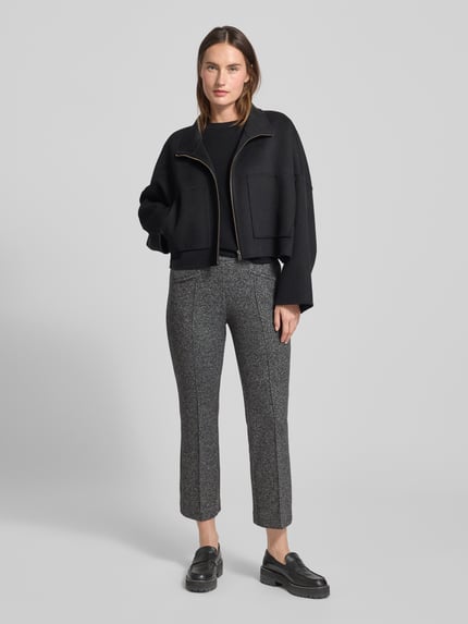 Frauenmodel trägt Slim Fit Stoffhose mit Viskose-Anteil Modell 'Jenny' von TONI in Grau mit Bügelfalten und Paspeltaschen, Ganzkörperansicht von vorne.