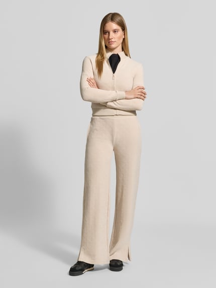 Frauenmodel trägt Slim Fit Sweatjacke mit Stehkragen Modell 'LAUDOMIA' von GUESS, Beige, Reißverschluss, Logo-Muster, Material-Mix, Ganzkörperansicht von vorne
