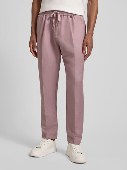 Männermodel trägt Regular Fit Hose aus Leinen-Viskose-Mix Modell 'NEIL' von Antony Morato in Rosa mit Bügelfalten, elastischem Bund, Ganzkörperansicht von vorne, Kontext: Herren Hose, Bundweite bei Größe 50: 44 cm, Innenbeinlänge bei Größe 50: 74 cm.