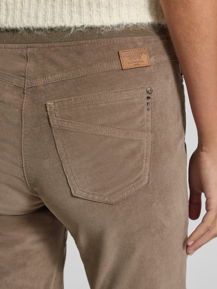 Frauenmodel trägt Slim Fit Jeans aus Baumwoll-Viskose-Mix Modell 'Pamina' von Raphaela By Brax in Beige mit sichtbarer Gesäßtasche, Nahaufnahme Oberkörper, Damen Slim Fit Jeans von Raphaela By Brax.