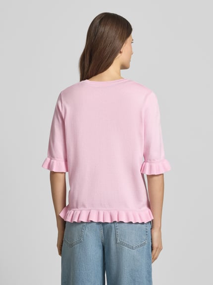Männermodel trägt Regular Fit T-Shirt aus Viskose-Mix Modell 'Katie' von FREE/QUENT, różowy kolor, dzianinowa faktura, falbany, półrękaw, okrągły dekolt, krój regular fit, widok całej sylwetki z tyłu, długość tyłu 56 cm, długość rękawa 33 cm.