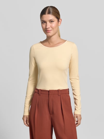 Vrouwenmodel draagt shirt met lange mouwen uit mix van katoen en elastaan van Marc Cain in lichtgeel, slim fit, ronde hals, ruglengte maat 36 is 50 cm, lange mouwen, effen design, voorkant geheel in beeld, Ganzkörperansicht von vorne.