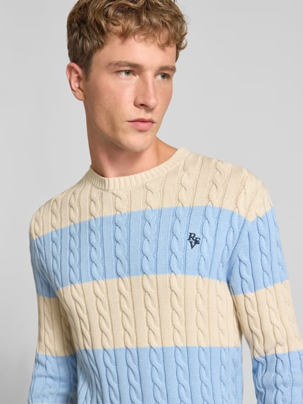 Männermodel trägt Slim Fit Strickpullover aus reiner Baumwolle mit Zopfmuster von REVIEW, beige-blaue Streifen, Label-Stitching, Nahaufnahme Oberkörper.