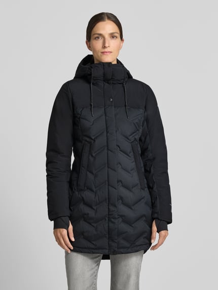 Frauenmodel trägt Mantel mit Stepp-Optik Modell 'Mountain' von Columbia, tailliert, Kapuze, Eingrifftaschen, schwarze Farbe, Ganzkörperansicht von vorne.