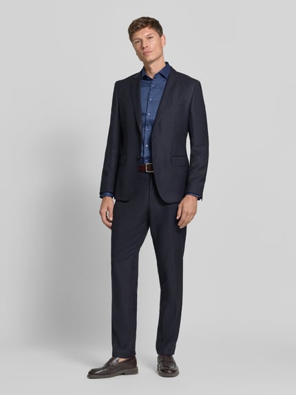 Männermodel trägt dunkelblaues Slim Fit Businesshemd mit Kentkragen von Seidensticker, unifarben mit Struktur, Ganzkörperansicht von vorne.