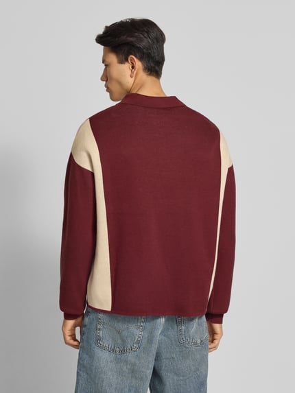 Männermodel trägt Strickpullover mit Polokragen und Label-Patch von PROHIBITED in Rot und Beige aus reiner Baumwolle, Relaxed-Fit, Ganzkörperansicht Rückansicht.