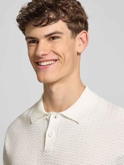 Männermodel trägt Relaxed Fit Poloshirt Modell 'FERDINAND' von Redefined Rebel aus Reine Baumwolle mit Knopfleiste, Nahaufnahme Oberkörper.